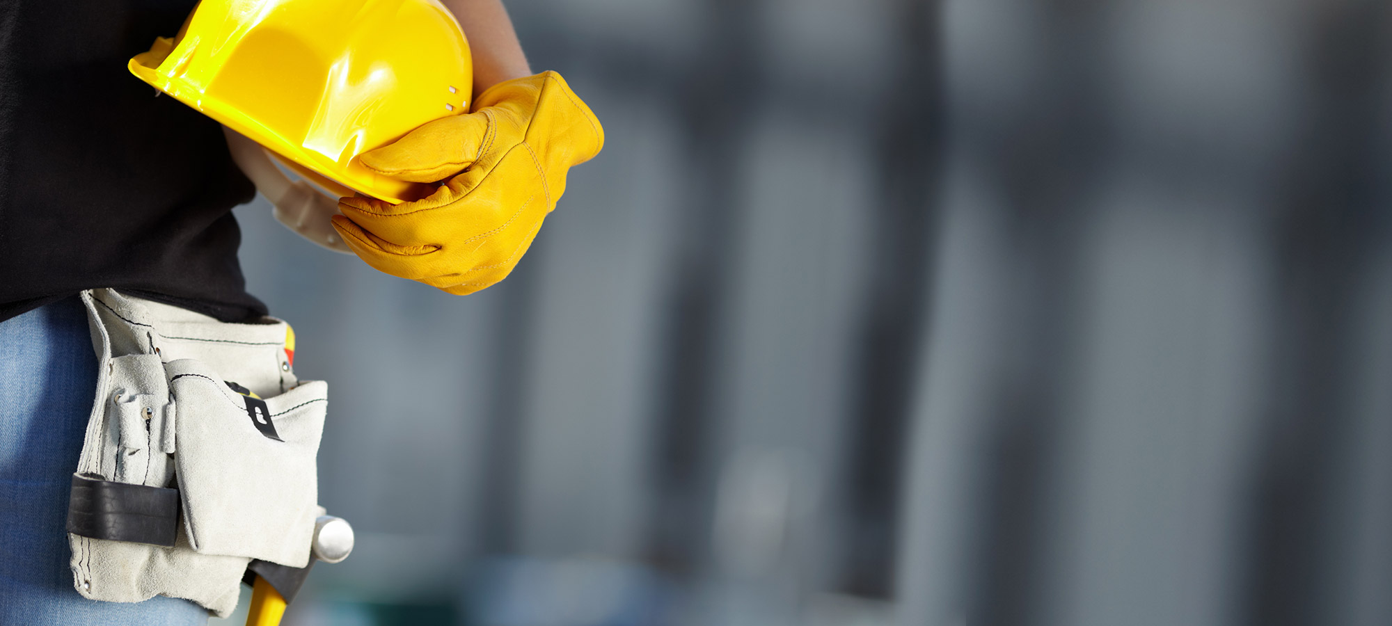 Mensch mit Schutzhelm, Arbeitshandschuhen und Arbeitsgürtel